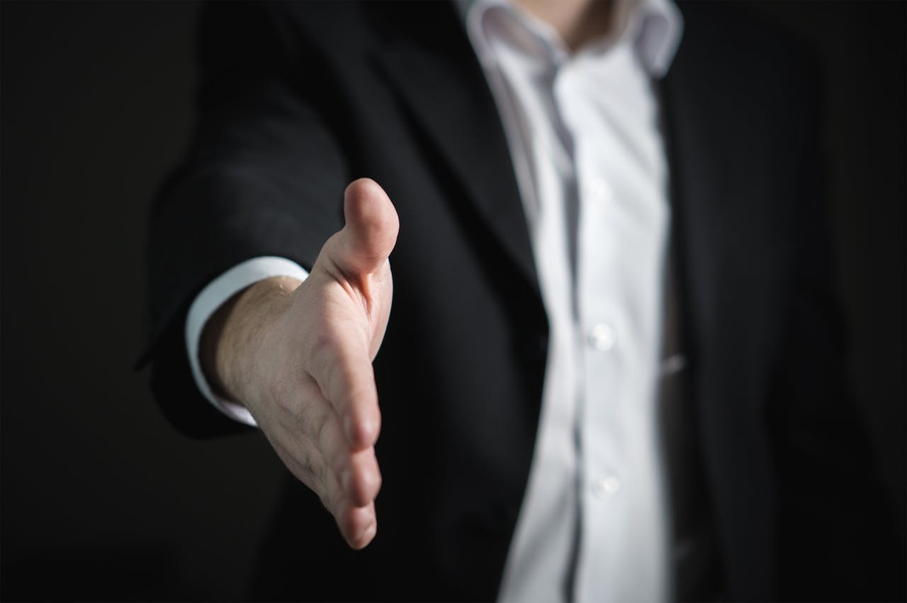 Services-01 Close-up of a businessman extending hand for a handshake, symbolizing agreement and partnership.