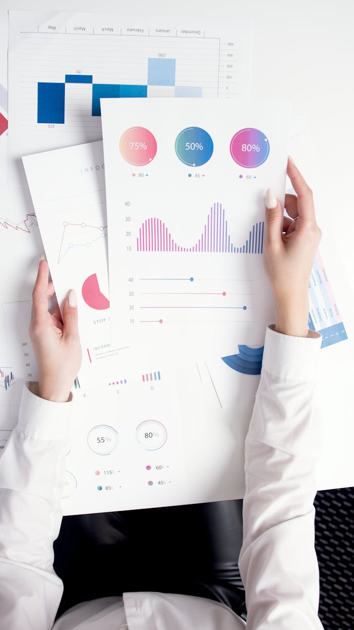 why-choose-us Close-up of hands analyzing colorful business data reports in an office setting.